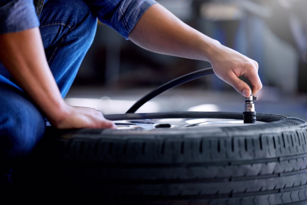 Air pressure, tire and mechanic working in garage with pump in hand. Man in auto service, vehicle c